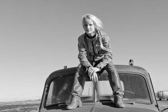 Blond Teenage Girl Sitting On Top Of A Truck Cab