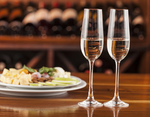 two glasses of champagne with a tray of cheese