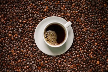 Coffee cup on roasted coffee beans background