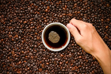 Coffee cup on roasted coffee beans background