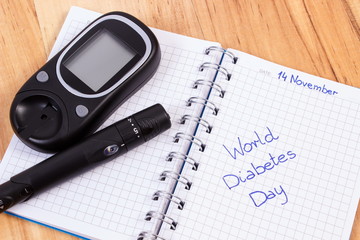 Glucometer with lancet device and world diabetes day written in notebook