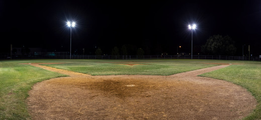 Panorama of empty baseball field at night from behind home pate - Powered by Adobe