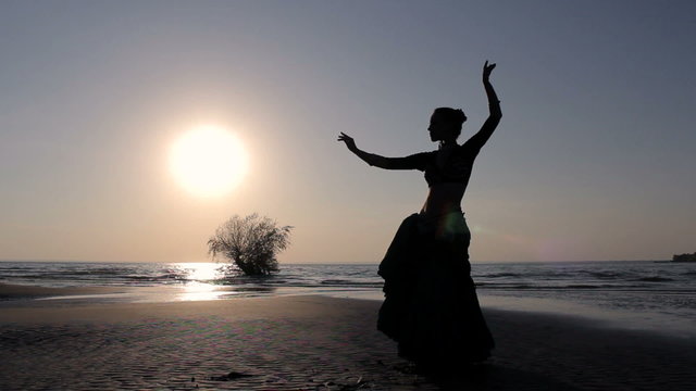 Silhouette girl dancing exotic dance on beach