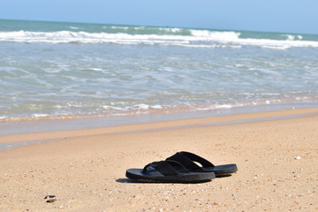 Fototapeta na wymiar Pair of Flip Flops on sandy Beach