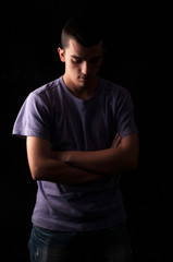 Serious young man standing with arms crossed on black background