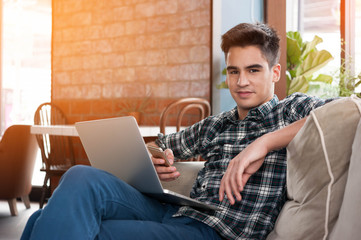 Businessman using smartphone and laptop writing on sofa in coffe