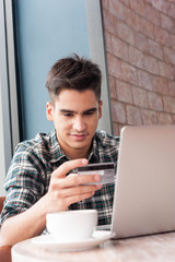 Businessman look at credit card while using laptop on wooden tab