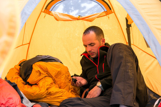 Climber inside Camping Tent Using Gadget Man lying on Sleeping Bag and Checking Oxygen Content in His Body