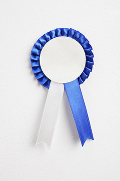 Blue award ribbon hanging on a white wall