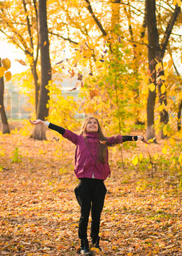 Smiling girl with autumn maple leaves at fall outdoors