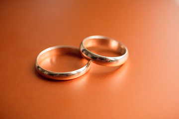 Two golden wedding rings isolated on orange background
