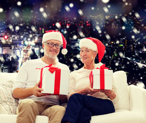 Obraz na płótnie Canvas happy senior couple in santa hats with gift boxes