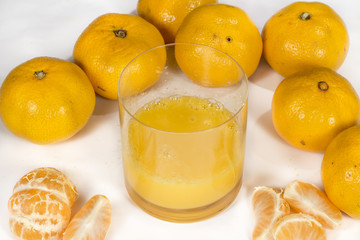 Glass with tangerine orange juice beside several fruits, on white © Alonso Aguilar