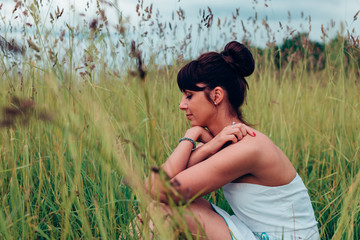 Fototapeta premium beautiful Russian girl sits in a meadow