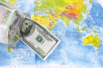 Obraz premium glass jar with dollars on the world map