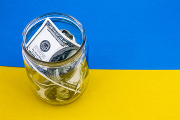 glass jar with dollars on the Ukrain flag