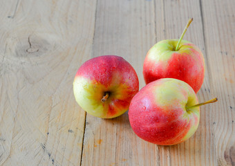 Three red apples  on wooden floor.