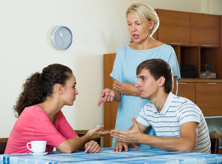 Upset female retiree watching adult kids quarrelling at home