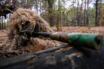 Soldier in camouflage suit with sniper rifle in forest/Soldier in special camouflage suit with sniper rifle in the forest aiming through the scope