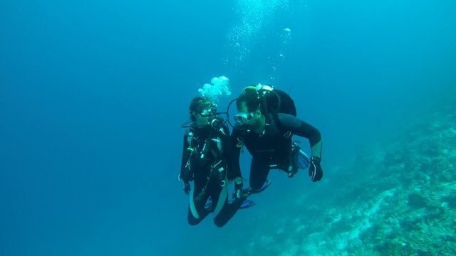 Divers man and a woman floating in the water holding hands, Indian Ocean, Maldives
