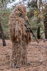 Sniper in camouflage suit with rifle in hands/Sniper standing in forest in camouflage suit with...