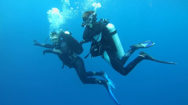 Divers man and a woman floating in the water column 
