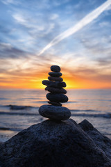 Stable vertical cairn at sunset on the sea