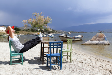 Woman is resting at characteristic restaurant on coast of the lake