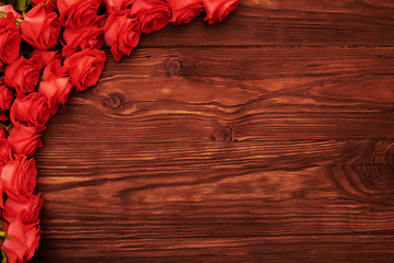 frame with red roses over wood background