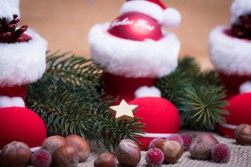 Weihnachtsdeko mit kleinen Stiefeln, Tannenzweigen und Nüssen