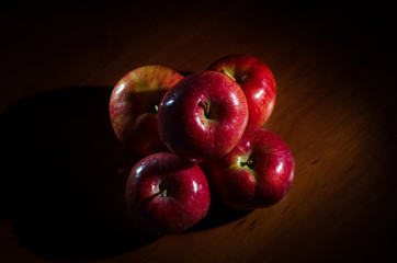 Red apples with water drops on a wooden table.