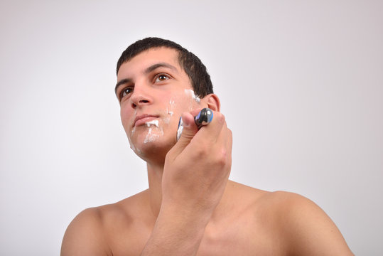 Handsome young man with lots of shaving cream on his face prepar