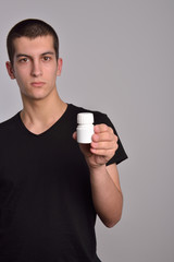 Young man holding a box of pills in his hand and shows the drugs