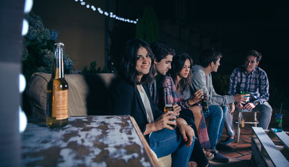 Woman holding beer and her friends talking in a party