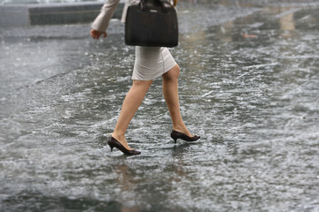 Woman walk on rain water, female feet with heels shoes walk on water when it rains