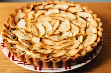 homemade delicious traditional apple pie with caramel on a plate on wood table and white background
