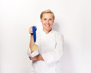 Woman in chef outfit and first prize medal smiling.
