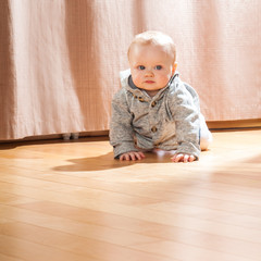 Beautiful baby in the interior. Baby crawling on the floor.