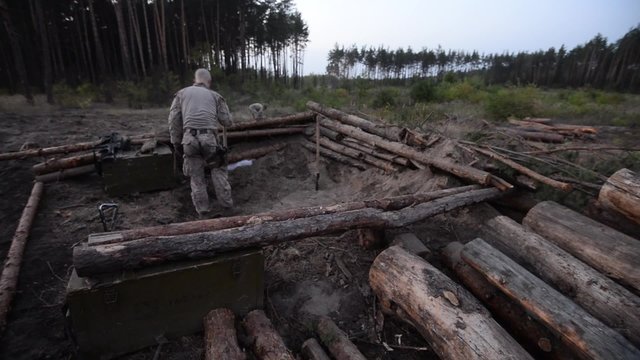 Soldier digs a trench/Soldier digs a pit to create fire point in forest at night
