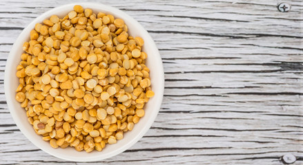 Raw Indian dhal in white bowl over wooden background