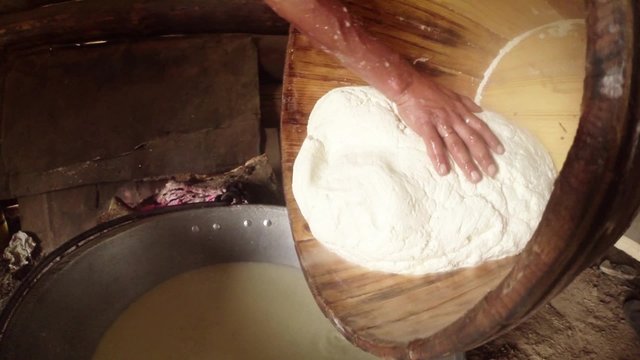 large piece of feta cheese in a wooden tub decanted from residual liquid on the background of the barracks of the Shepherds