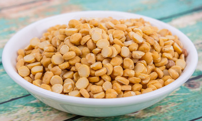 Raw Indian dhal in white bowl over wooden background