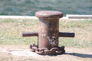 Old metal mooring post attached to a concrete dock.