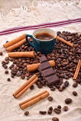 Cup of hot coffee with cinnamon sticks, bitten bar of chocolate