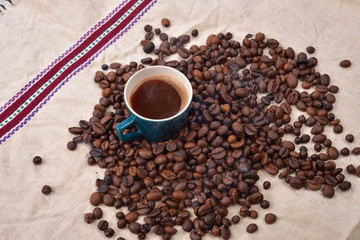 Coffee beans and green cup on textured background. copy space