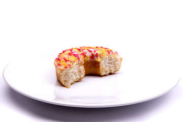 Partially eaten iced ring donut on a plate