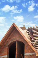 House under construction. Workers installing fibreboard on the roof