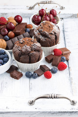 chocolate muffins and fresh berries on white wooden table