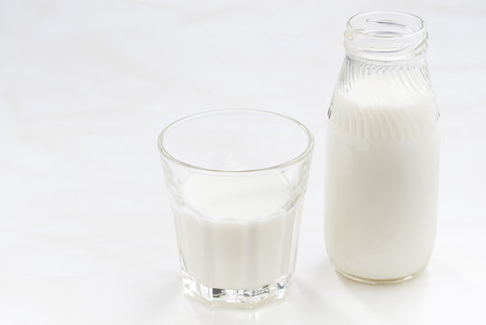 bottle and glass of milk on a white background