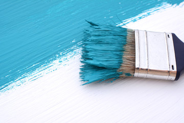 Close-up of paintbrush painting a white board blue